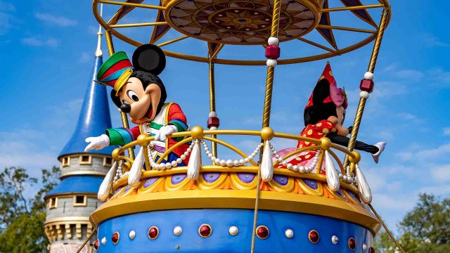 Mickey and Minnie waving from their float in the Festival of Fantasy Parade in Magic Kingdom